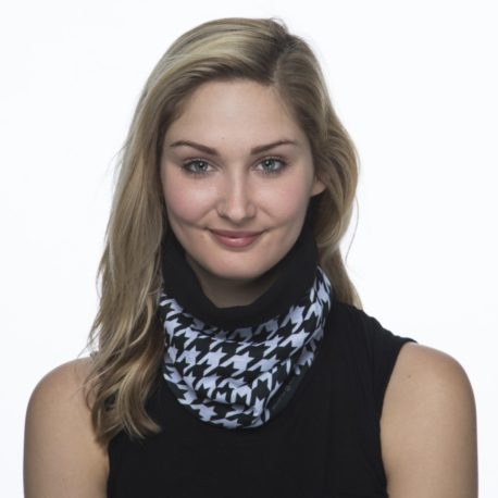 image of a female model wearing a fleece lined multifunctional scarf with a black and white houndstooth pattern on the outer layer with black fleece lining